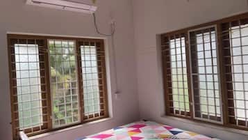Una habitación con una cama, dos ventanas con barrotes y un equipo de aire acondicionado en la pared.