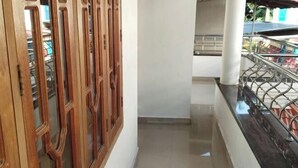 Un pasillo estrecho con una puerta de madera y una barandilla de metal a un lado.