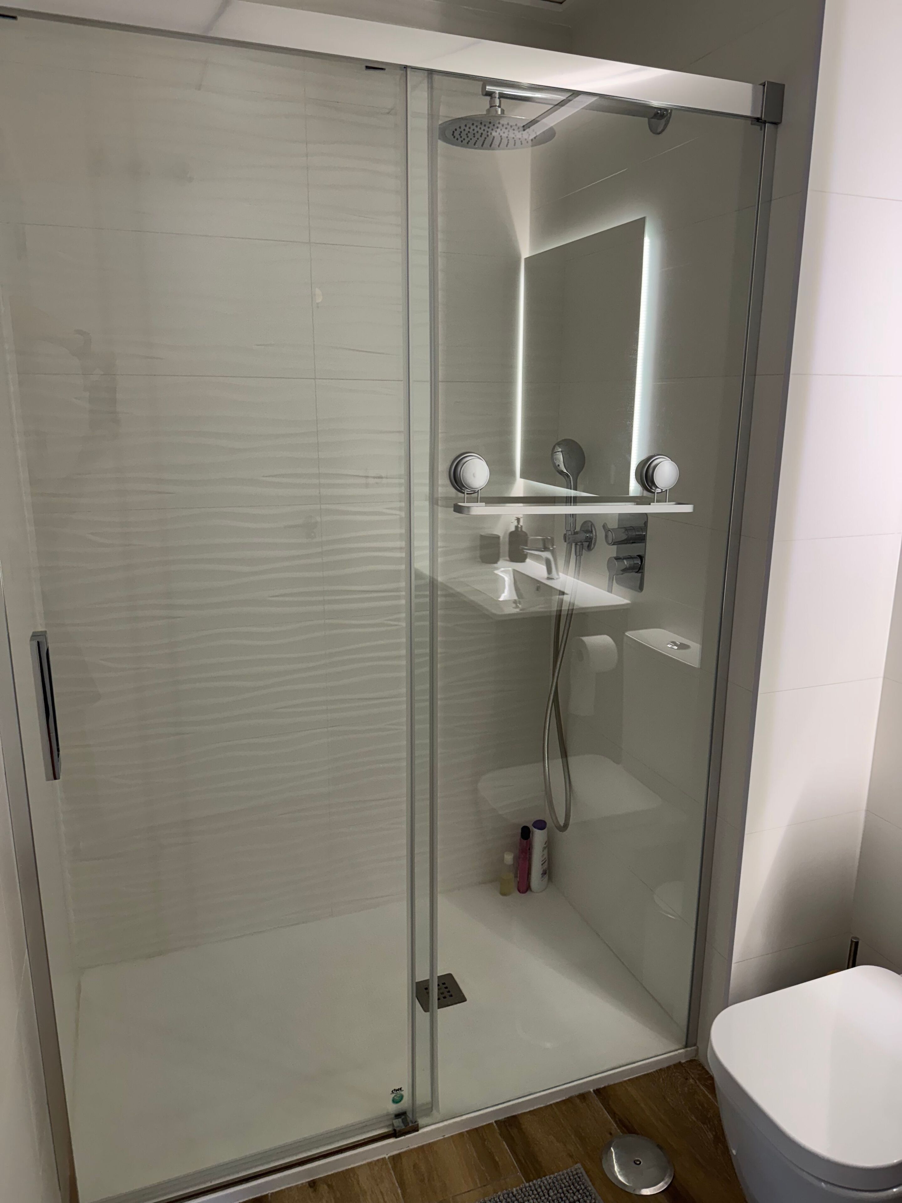 Ein modernes Badezimmer mit einer Duschkabine, Toilette und einem Waschbecken mit Spiegel.