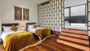 A hotel room with two beds, wooden flooring, a decorative wall panel, and a staircase leading to an outdoor area. - Baan Santisuk (Phuket)