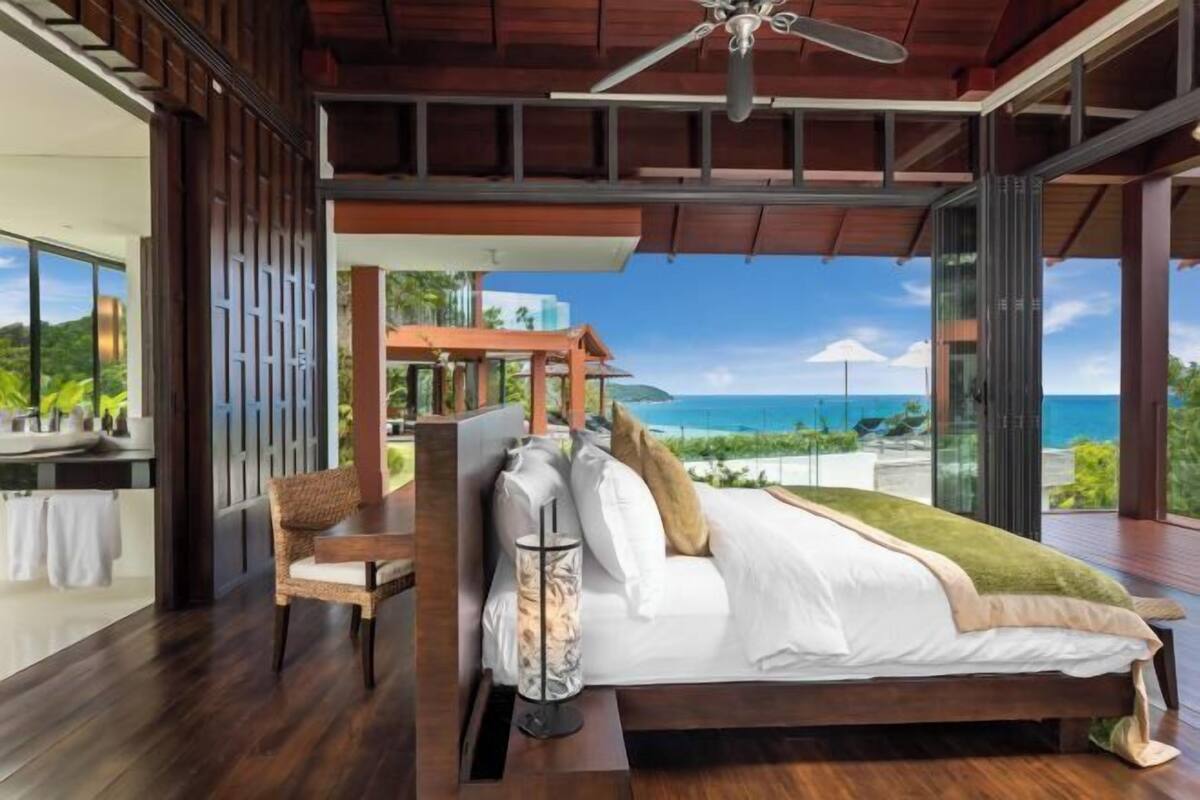 A bedroom with a large bed, a chair, and a view of the ocean.