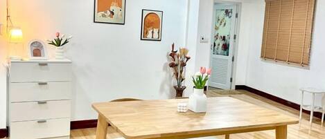 Un comedor con una mesa y sillas de madera, un armario blanco y adornos en la pared.