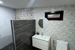 A bathroom with a white sink, a mirror, and a toilet. - Jaiko home&hotel (Khlung)