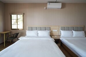 Una habitación de hotel con dos camas, un escritorio, una silla y una ventana.