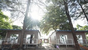 A row of cabins with a dirt path between them, surrounded by trees. - STARHOUSE (Kudat Division)