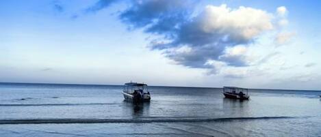 A calm sea with two boats and a clear sky.