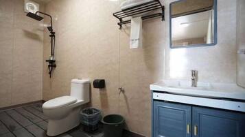 A bathroom with a toilet, shower, sink, and cabinet.