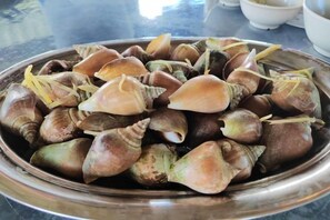 A metal bowl containing a collection of snails with their shells. - STARHOUSE (Kudat Division)