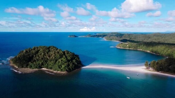 An aerial view of a coastal area with a small island surrounded by clear blue waters and a sandy beach. - STARHOUSE (Kudat Division)