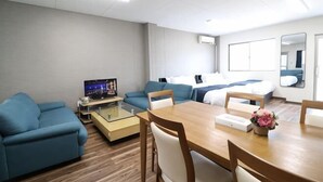 Une chambre d’hôtel comprenant un lit, un canapé, une table à manger, une télévision et un miroir.