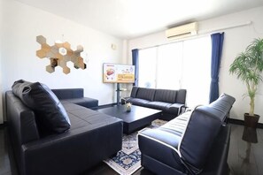Ein modernes Wohnzimmer mit einer Couch, Sesseln, einem Couchtisch und einer Wanddekoration.