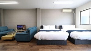 Une chambre d’hôtel avec deux lits, un canapé, une télévision et une fenêtre.
