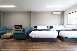 Ein Hotelzimmer mit zwei Betten, einem Sofa, einem Fernseher und einem Fenster.