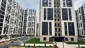 A modern apartment building with a central entrance, multiple balconies, and a small courtyard with greenery. - Ali Boutique Guesthouse (Almaty)