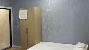 A bedroom with a bed, a wardrobe, and a door. - Ali Boutique Guesthouse (Almaty)
