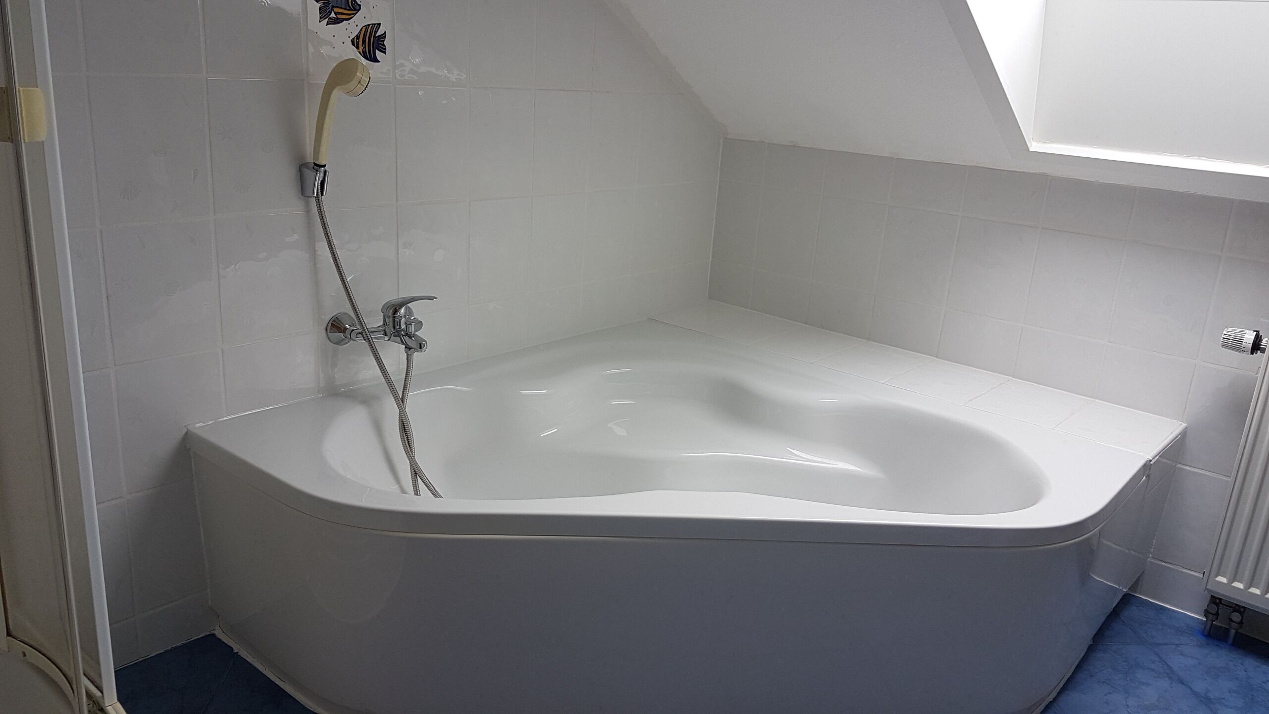 A modern bathroom with a freestanding bathtub, a showerhead, and a radiator.