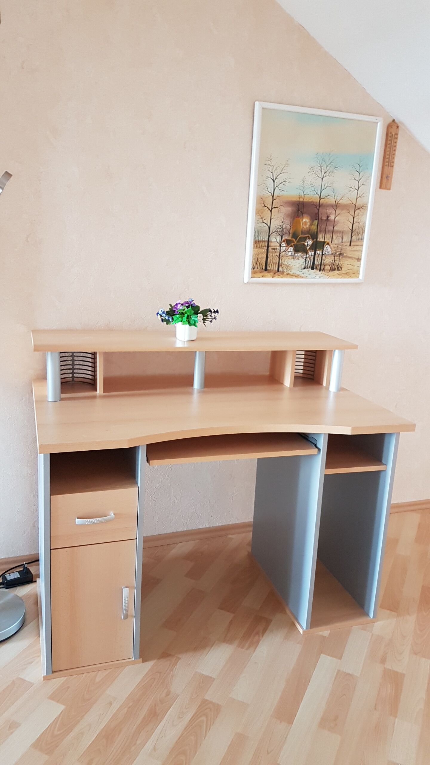 A corner desk with a drawer, a shelf, and a small potted plant.