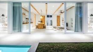 A modern house with a spacious interior, large sliding glass doors, and a well-lit living area. - ULU 1 · 2br villa (Bali)
