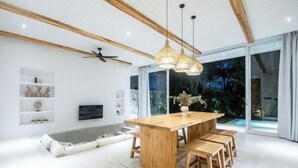 A modern kitchen with a wooden island, pendant lights, and a large window overlooking a garden. - ULU 1 · 2br villa (Bali)