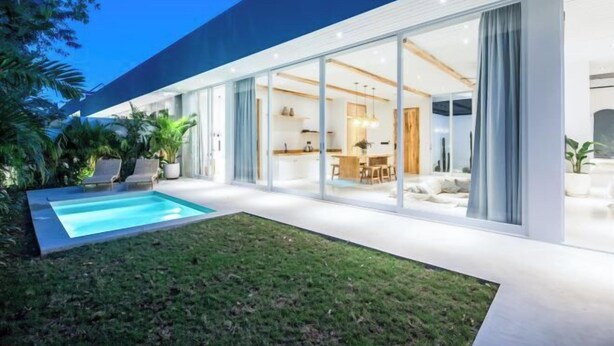 A modern house with a swimming pool, large glass doors, and a well-maintained lawn. - ULU 1 · 2br villa (Bali)