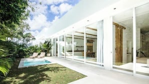 A modern house with a glass-enclosed patio, a swimming pool, and a lush garden. - ULU 1 · 2br villa (Bali)