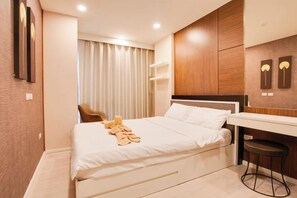 A hotel room with a bed, a desk, a chair, and a window with curtains. - Palm Springs Nimman (Chiang Mai)
