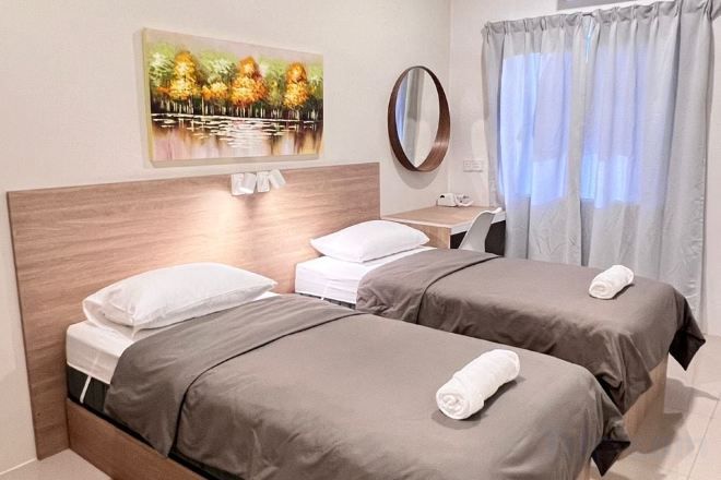Habitación de hotel con dos camas, un escritorio, un espejo y un cuadro en la pared.