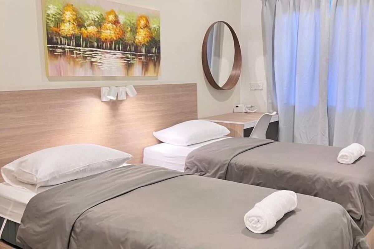 A hotel room with two beds, a desk, a mirror, and a painting on the wall.