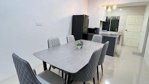 A modern kitchen with a black refrigerator, a dining table with six chairs, and a small island with a sink. - T2 House Kuantan (Kuala Kuantan)