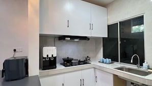 A modern kitchen with white cabinets, a built-in stove, a coffee maker, and a window with a view. - T2 House Kuantan (Kuala Kuantan)