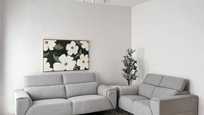 A modern living room with a grey sofa, a ceiling fan, and a framed floral artwork on the wall. - T2 House Kuantan (Kuala Kuantan)