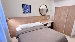 A bedroom with a bed, a desk, a chair, a wardrobe, a round mirror, and a framed picture on the wall. - T2 House Kuantan (Kuala Kuantan)