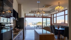Une cuisine moderne dotée d’un îlot central, de grandes fenêtres et d’un coin repas avec des chaises et une table.