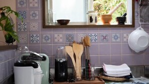 Cozinha com janela, backsplash em azulejo e diversos utensílios e recipientes.