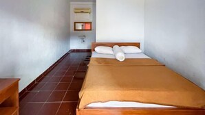 A small, narrow room with a single bed, a wooden nightstand, a wall-mounted sink, and a tiled floor. - Guest House Surya Ayu Permai Buleleng Mitra RedDoorz (Bali)