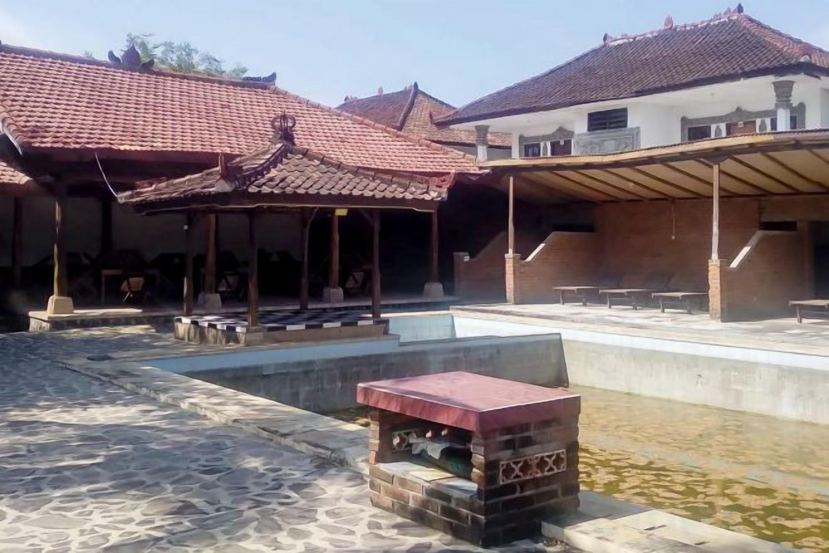 A courtyard with a tiled roof structure, a pool, and a stone pathway.