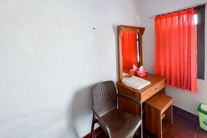 A small room with a wooden desk, a chair, a mirror, and a window with red curtains. - Guest House Surya Ayu Permai Buleleng Mitra RedDoorz (Bali)