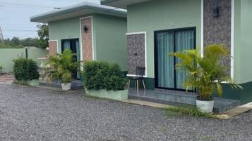 A row of two-story buildings with a gravel driveway, potted plants, and a chair outside.