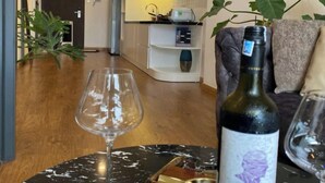 A living room with a wine bottle and glass on a marble table, a sofa, and a plant. - Apartments in District 2-The Sun Avenue (Ho Chi Minh City)