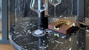 A room with a bed, a framed artwork on the wall, a bottle of wine, two wine glasses, and a small wooden box with keys on a marble table. - Apartments in District 2-The Sun Avenue (Ho Chi Minh City)