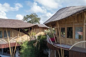 A wooden building with a sloped roof, large windows, and a balcony with a wicker chair. - Clan Living - the Lovers Ubud Private Villas (Bali)