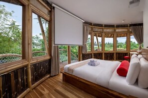 A bedroom with a large bed, a view of greenery, and a projector screen. - Clan Living - the Lovers Ubud Private Villas (Bali)