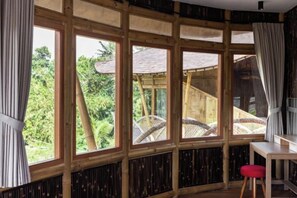 Una habitación con ventanas amplias, una pared de madera, una mesa y una silla roja.