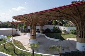 An outdoor patio area with a covered seating area, planters, and a curved pathway. - Clan Living - the Lovers Ubud Private Villas (Bali)