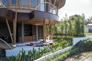 A modern house with a circular structure, a covered outdoor seating area, and a landscaped garden. - Clan Living - the Lovers Ubud Private Villas (Bali)