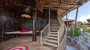Un interior de madera con una escalera en espiral, un banco con cojines rojos y un suelo con diseño.