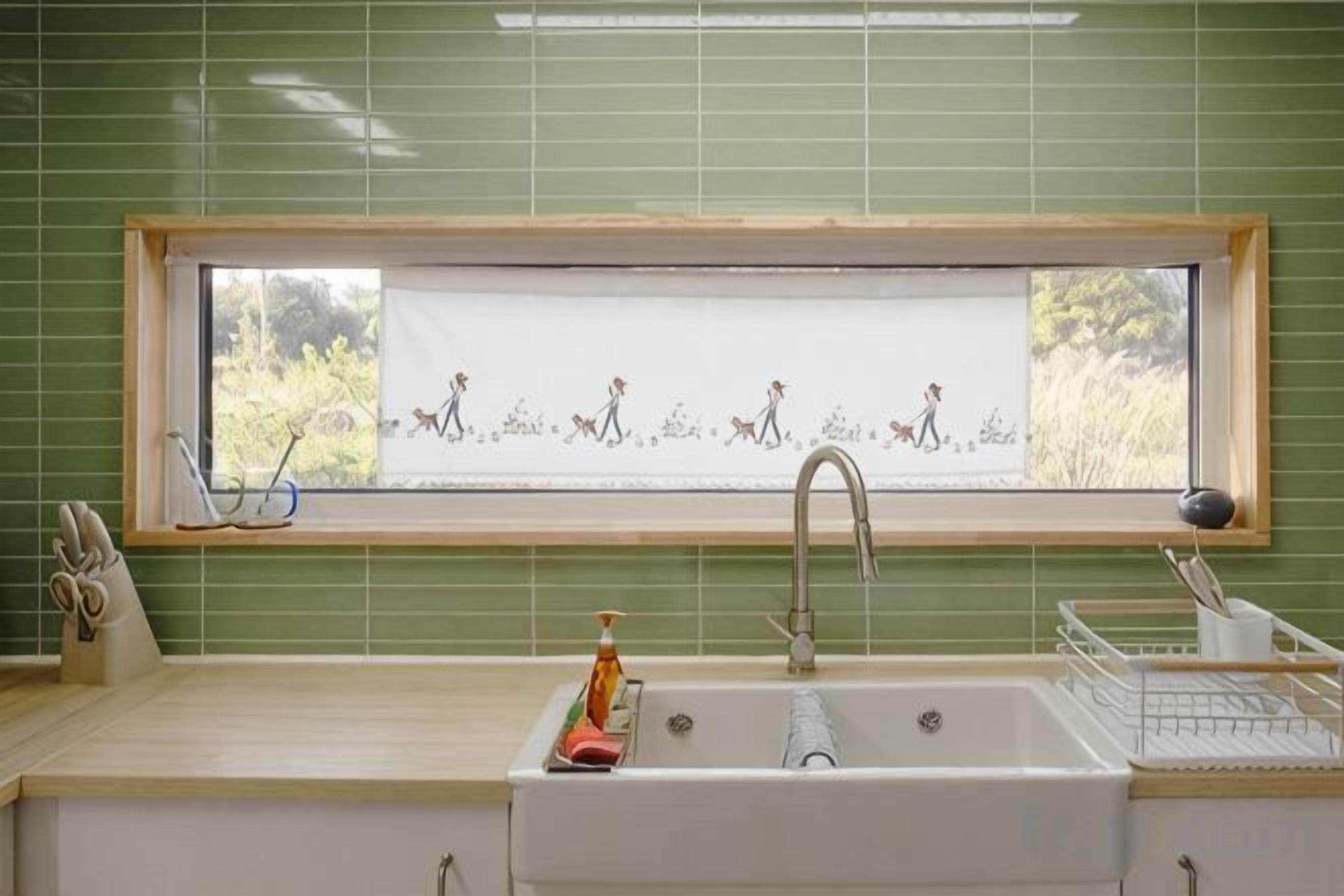 A kitchen with a window, sink, and a window blind with a pattern.