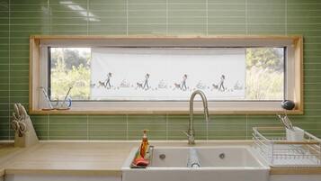 A kitchen with a window, sink, and a window blind with a pattern.