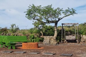 Un parc avec un banc vert, une balançoire en bois et un arbre.