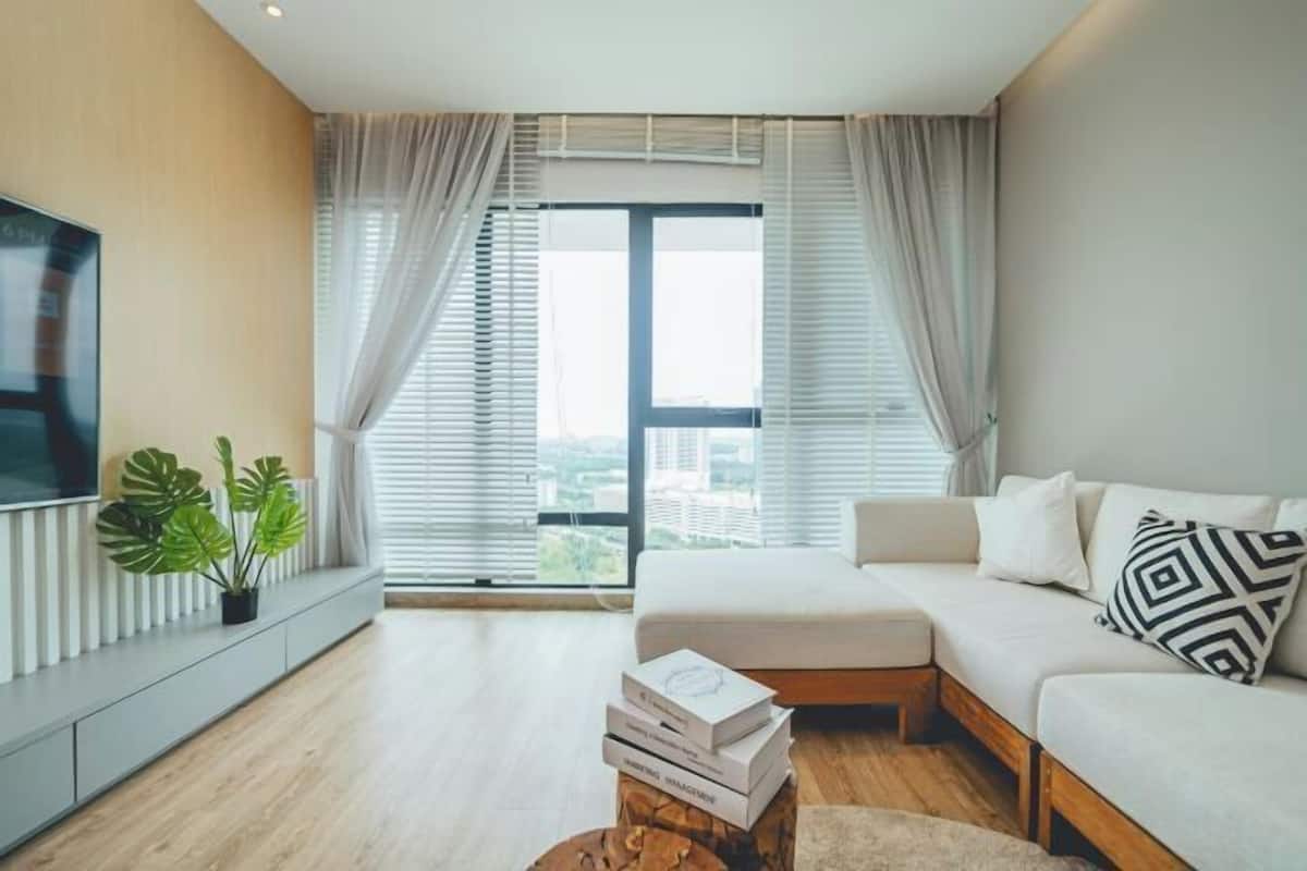 A modern living room with a sofa, a coffee table, a TV, and a large window with curtains.